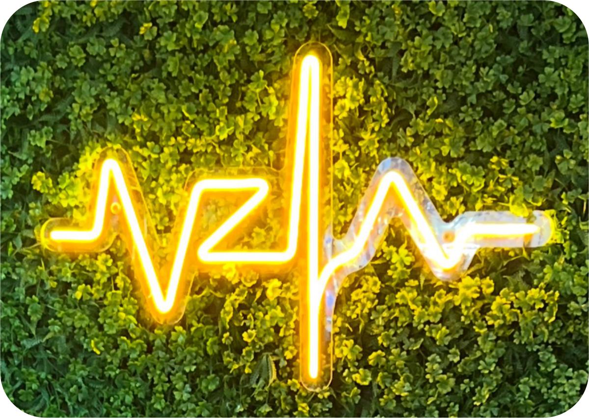 Neón amarillo con forma de electrocardiograma sobre vegetación