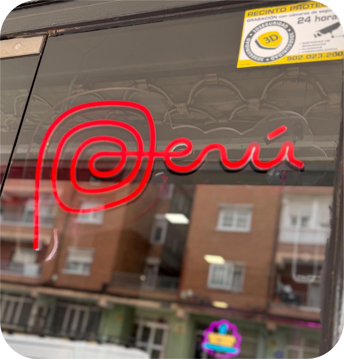 Neón rojo con texto Perú en estilo cursivo sobre escaparate